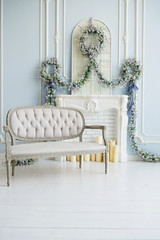 Classic gray sofa in a luxurious white room. artificial fireplace. on the fireplace. the room is decorated with flowers