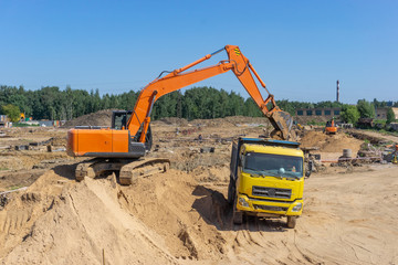 Obraz premium Excavator at the construction site will load the truck with sand