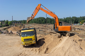 Excavator at the construction site will load the truck with sand