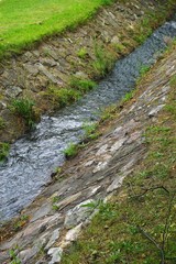 Stream flowing through a stone-lined ditch