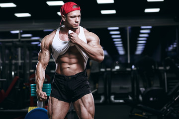 Fototapeta na wymiar Muscular athletic bodybuilder fitness model posing and exercises in gym