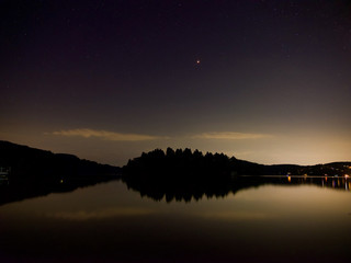 夜の湖畔にて、島の真上に火星と星座、湖面はオレンジ色で鏡の様に映っす。