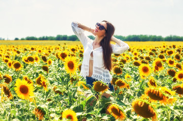 Fototapeta premium Beautiful young girl outdoors . A young girl is having fun in the field with flowering sunflowers .