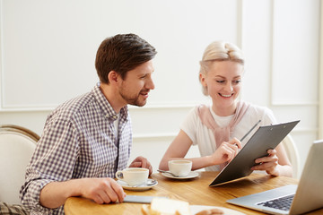 Obraz premium Happy excited young colleagues in casual clothing discussing strategy at coffee break: positive lady showing plan and explaining idea