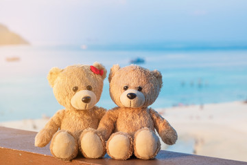 Two teddy bears sitting sea view. Love and relationship concept. Beautiful white sandy beach in the summer.