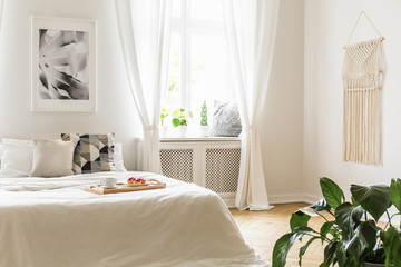 Breakfast tray with pastries and coffee on a cozy, white bed in a bright and peaceful bedroom...