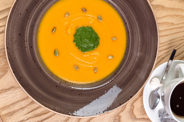 Bowl of pumpkin soup on rustic wooden background.