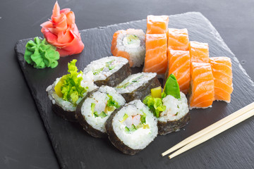 Japanese restaurant, sushi roll on black slate plate.