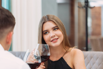 Beautiful young couple with glasses of red wine in luxury restaurant