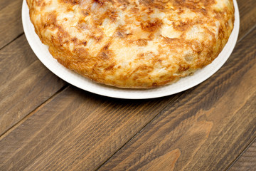 Spanish potato omelette on rustic brown wooden background. Typical spanish food.