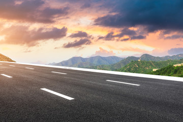 Empty asphalt road and great wall with mountains at sunset