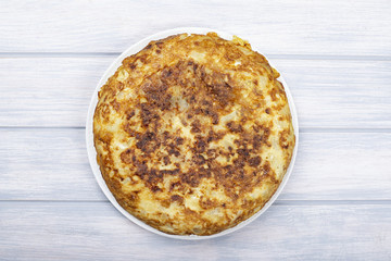Spanish potato omelette on white wooden background. Typical spanish food.