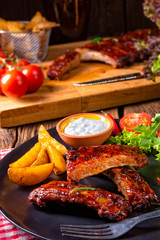 bbq spareribs on the plate with green salad and white sauce.