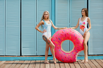 Two happy girls rest on the sea. happy girls on the beach. beautiful girlfriends with inflatable swim ring in shape of a donut