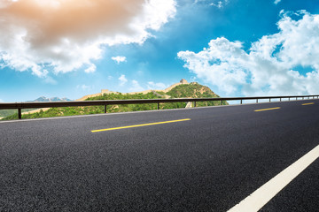 Empty asphalt road and great wall with mountains under the blue sky