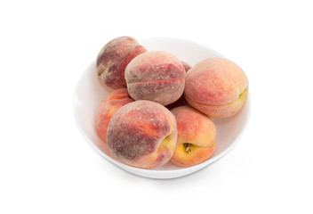 Fresh peaches in bowl on a white background