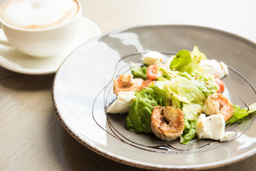 Big shrimp and green salad with cheese on plate