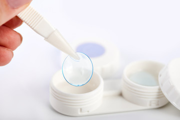 Contact lens, contact lens case, tweezers on white background. Correction of vision.