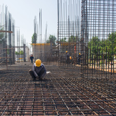 worker on strengthens and connects the reinforcement for the pouring concrete foundation. candid,...