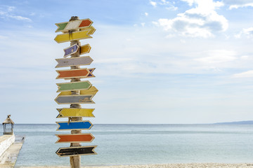 Multiple blank signs on a wooden pole in the beach.place for text. - Powered by Adobe