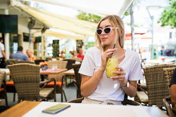 Young Woman drinking cocktail lemonade in cafe