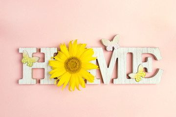 Decorative word Home with butterflies and sunflower on pink background. Copy space.