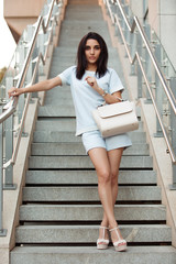 Woman in shorts and high heels holding ivory bag