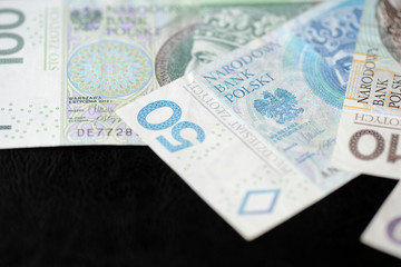 Several banknotes of Polish zloty on a dark background close up