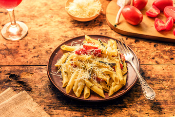 Traditional Italian rustic lunch - pasta penne with grilled zucchini and tomatoes and a glass of homemade wine