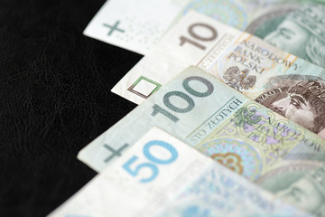 Several banknotes of Polish zloty on a dark background close up