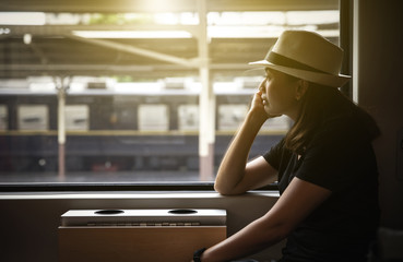 Young pretty woman traveling lifestyle at a train and looks out the window retro style,...