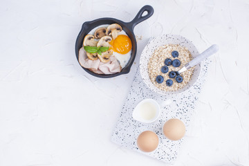 A delicious healthy breakfast of eggs and oatmeal with berries, on a light background. Top view. Copy space,
