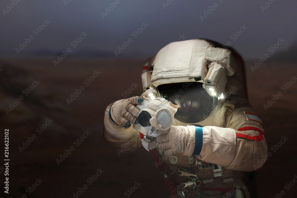 Poster spaceman with a camera in a space suit on the planet mars. astronaut takes pictures a new planet.