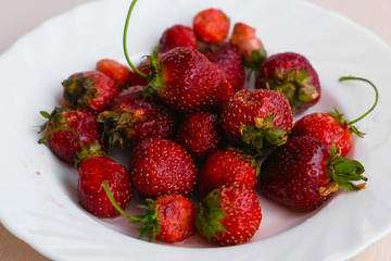 Juicy appetizing tasty strawberry on a white plate. Close-up.