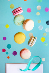 Colorful macarons and confetti flying from paper bag.