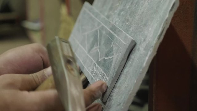 Nepalese craftsman working on traditional Mani slate stone in Kathmandu, Nepal.