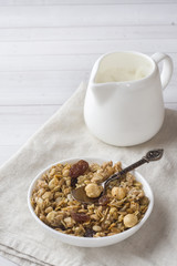 Dry Breakfast of oat flakes, granules and nuts. Muesli in a plate and a milk jug with yogurt.