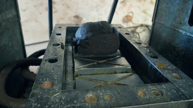 Man places garbage onto a pressing machine, close up.