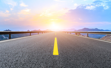 Empty asphalt road and great wall with mountains at sunset