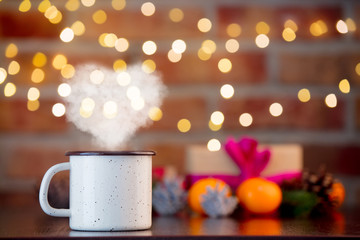 cup of hot drink with heart shape steam on background with fairy lights in bokeh. Christmas Holiday season