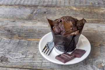Chocolate muffin on wooden background. Copy space