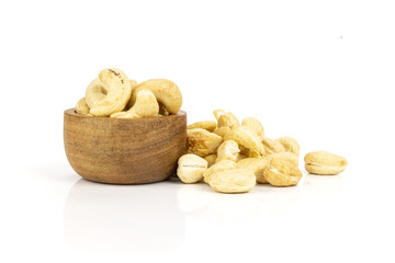 Lot of whole raw cashew nut heap behind with wooden bowl isolated on white background