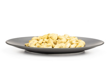 Lot of whole raw cashew nut on grey ceramic plate isolated on white background
