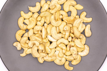 Lot of whole raw cashew nut on grey ceramic plate flatlay isolated on white background