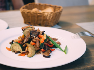 Pork roast with vegetables on white plate in table