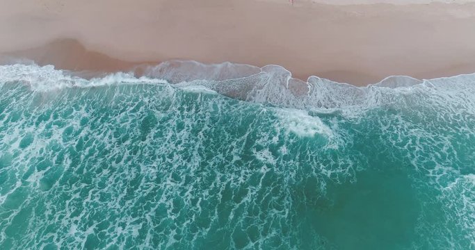 Aerial drone view of beautiful tropical beach with waves crashing during sunny summer day