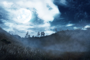 Misty hill with dark cloud and full moon on the night
