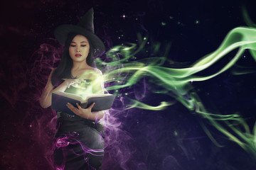Pretty asian witch woman reading the incantation in book