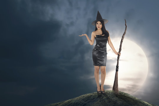 Young asian witch woman with hat and broomstick
