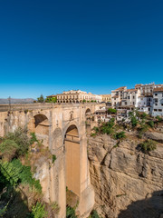 Fototapeta na wymiar Panorama view of the Puente Nuevo bridge and the houses built on the edge of the cliff, in the ancient city of Ronda, Spain